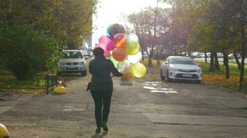 ein schleppend Bewegung von ein Frau Gehen Nieder das Straße mit bunt Luftballons video