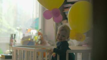 Baby girl playing with balloons in the crib video