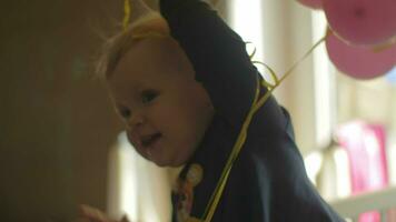 A baby girl in a crib playing with balloons video