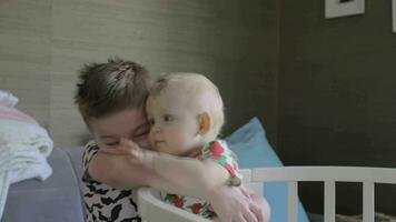 A boy hugging his baby sister in a crib video