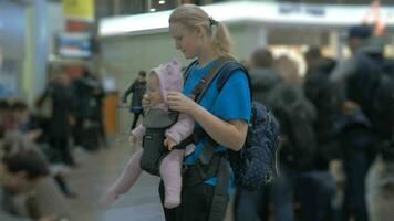 schattig baby in een baby vervoerder Bij luchthaven video