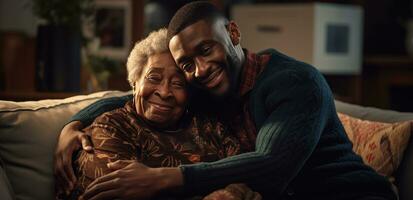 negro hombre abrazando un más viejo mujer en sofá en el familia. foto