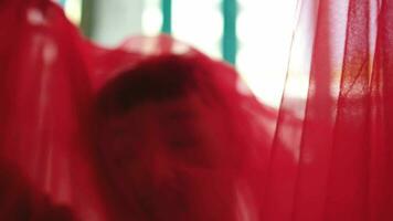 an Asian man in a red cloth dances with a lithe and agile body in front of a window video