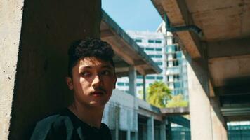 an Asian man standing and leaning on a concrete wall with a sad face video