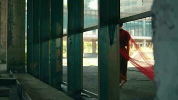 an Asian man walks in an abandoned building with a red cloth hanging down video