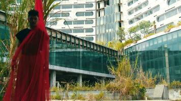 un asiatique homme permanent avec une rouge tissu enveloppé autour le sien corps tandis que dans de face de un abandonné bâtiment video