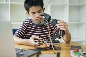 Asian teenager doing robot project in science classroom. technology of robotics programing and STEM education concept. photo