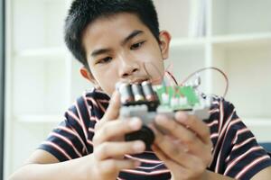 Asian teenager doing robot project in science classroom. technology of robotics programing and STEM education concept. photo