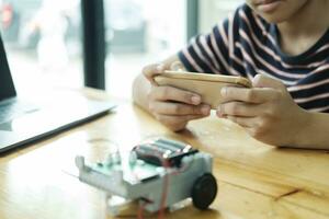 Asian teenager doing robot project in science classroom. technology of robotics programing and STEM education concept. photo