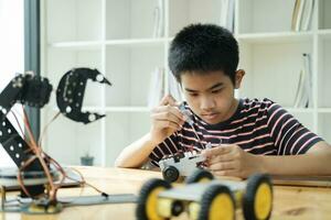 Asian teenager doing robot project in science classroom. technology of robotics programing and STEM education concept. photo