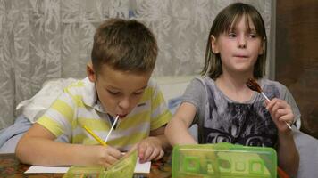 Boy and girl with lollipops drawing with colour pencils at home video