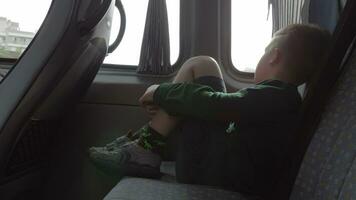 A boy sitting on a backseat of a car looking at a window video