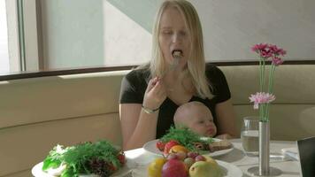 uma mulher com uma bebê em dela colo é tendo uma refeição video