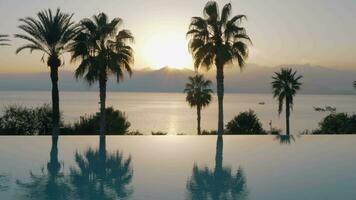 un' steadicam tiro di un Aperto piscina confine e il tramonto di il mare dietro a esso video