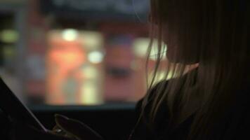 Woman with mobile in the car going in evening city video