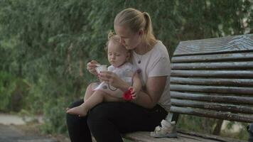 Mum giving yogurt to baby daughter in the park video