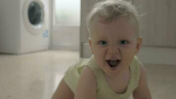 Happy active baby girl crawling and playing in the kitchen at home video