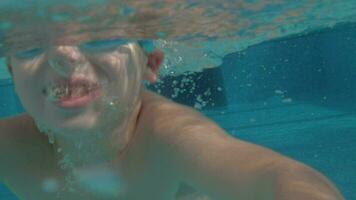 ein schleppend Bewegung von ein Junge Tauchen im und aus das öffnen Schwimmbad video