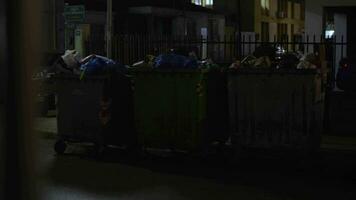 lleno contenedores de basura en el calle de pequeño ciudad, noche ver video
