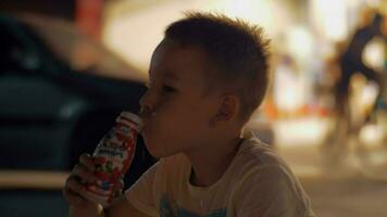 hambriento niño Bebiendo yogur al aire libre a noche video