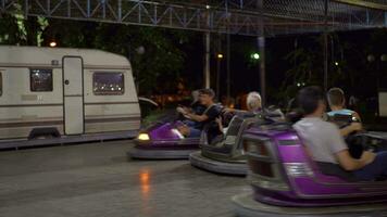 Adults with children having fun driving bumper cars at fun fair video