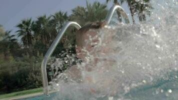 alegre niño salpicaduras agua en nadando piscina al aire libre video