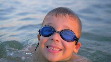 sonriente niño en gafas de protección nadando en el mar video