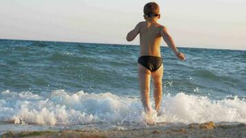 niño disfrutando vacaciones en el costa y corriendo dentro mar a nadar video