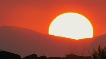 rood lucht tafereel met zon schuilplaats achter de bergen video