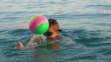 enfant en jouant avec Balle lorsque baignade dans le mer sur vacances video