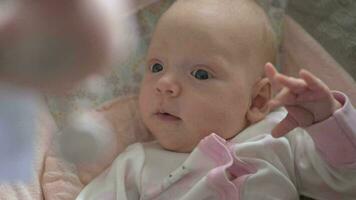 Lovely calm baby girl looking at toys over the head video