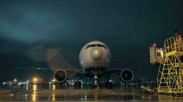 View to the cockpit and engines of parked airliner in airport at night video