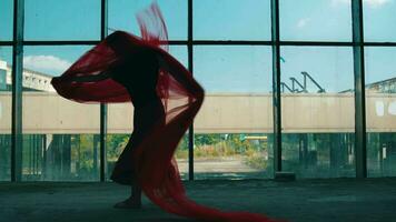 un asiático hombre bailando con un rojo paño cubierta su cuerpo en frente de un edificio ventana video