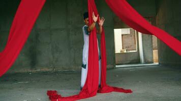 an Asian man dancing with a hanging red cloth very agile and energetic in an old building video