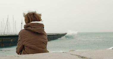 solitário Garoto olhando às oceano sentado em a costa video