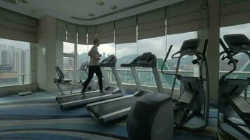 Clip of woman on the treadmill in fitness centre looking at window with cityscape Hong Kong, China video