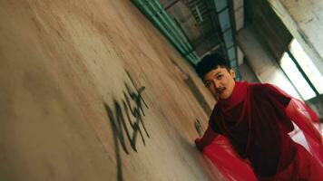 an Asian man running with a happy and cheerful face in an alley of an empty building video