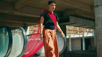 an Asian man walking from the escalator with a red cloth hanging down to the ground video