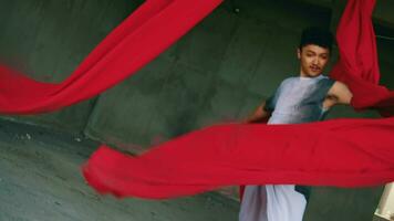 an Asian man playing and hanging from a red rope with a cheerful face video