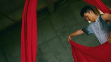 un asiatico uomo danza con un' sospeso rosso stoffa molto agile e energico nel un vecchio edificio video