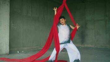 an Asian man dancing with a hanging red cloth very agile and energetic in an old building video