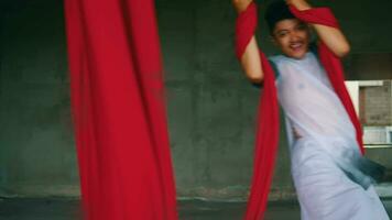 an Asian man dancing with a hanging red cloth very agile and energetic in an old building video