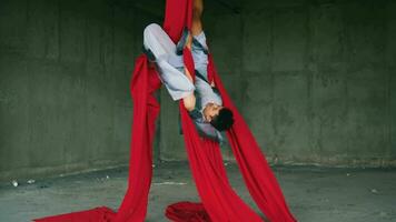 a ásia homem jogando e suspensão a partir de uma vermelho corda com uma alegre face video