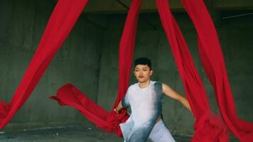 an Asian man playing and hanging from a red rope with a cheerful face video