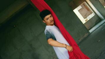 an Asian man playing and hanging from a red rope with a cheerful face video