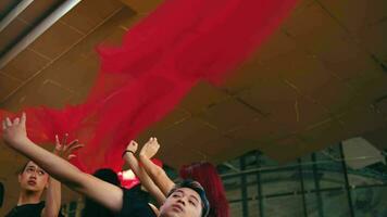 un grupo de asiático bailarines captura el volador rojo paño y danza con eso video