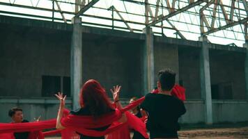 a group of Asian men are playing with red cloth ropes with their friends in a tug of war video