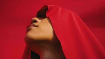 an Asian man with his face and eyes covered by a red veil in front of a red background video