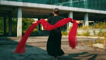 an Asian man running and dancing with a red scarf on his body that flies in the wind in an abandoned building video