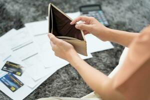 mujer estresada y con dolor de cabeza con grandes facturas o facturas sin dinero para pagar los gastos y la deuda de la tarjeta de crédito. escasez, problema financiero, quiebra, hipoteca, préstamo, en quiebra, pobre, billetera vacía foto